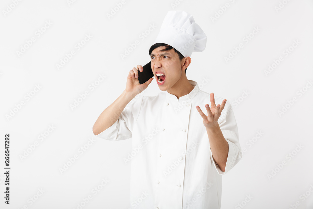 Image of irritated chinese chief man in white cook uniform and chef's hat talking on mobile phone Image of irritated chinese chief man in white cook uniform and chef's hat talking on mobile phone