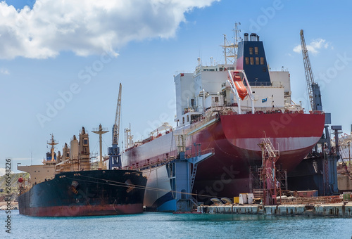 Bulk Carrier On Dry Dock In Shipyard.Heavy lifts cargo ship temporary  laid up next to dry dock. Stock Image.