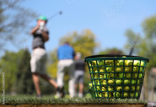 A jumbo bucket of golf balls sit at the end of a golfing practice facility