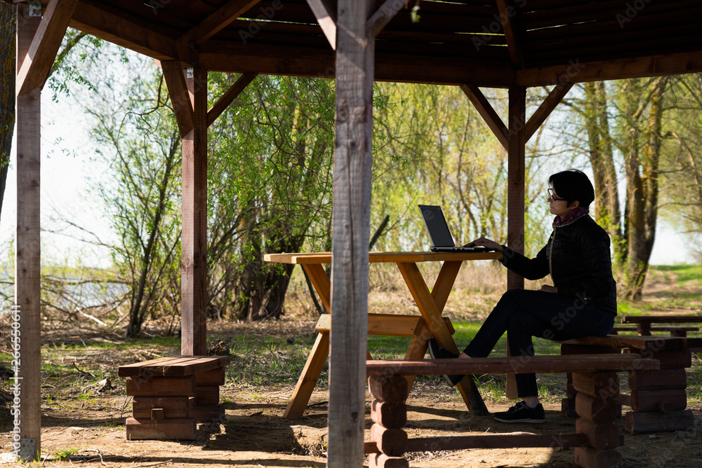 Girl using lap top among nature. Time online. The girl is sitting at the computer in the summer house. Girl using lap top among nature. Time online. The girl is sitting at the computer in the summer house.