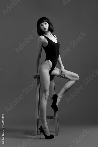 Beautiful model posing near high chair in studio.