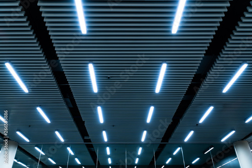 Leading lines and low light view. Fluorescent lamps open in row on the ceiling beautiful and modern inside the building.