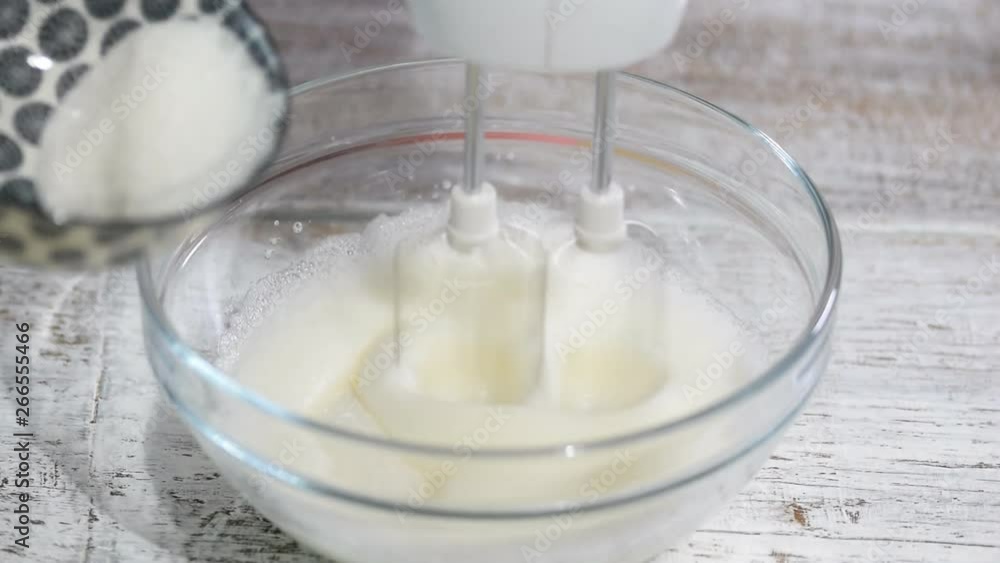 Female chef whipping egg whites with sugar in a bowl. Female chef whipping egg whites with sugar in a bowl.