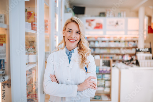 Cheerful pharmacist standing in pharmacy drugstore. photo