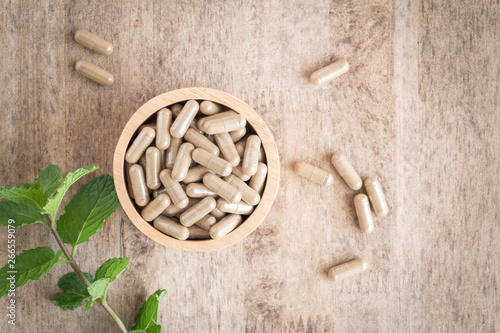 Herbal capsules  in cup on wooden table background . Top view of medicine for healthy. photo