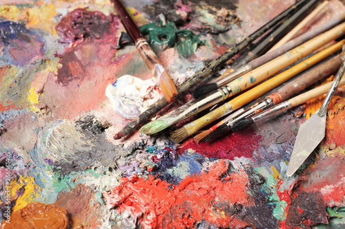 Paintbrushes closeup, artist palette and multicolor paint stains.