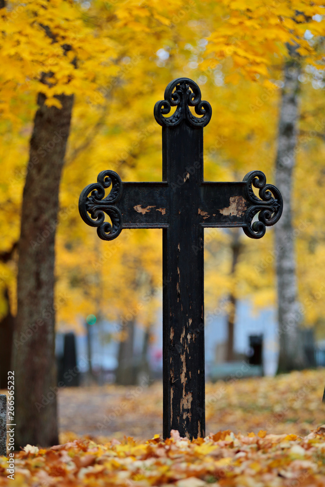 An old memorial on an ancient graveyard with beautiful yellow maple trees in autumn