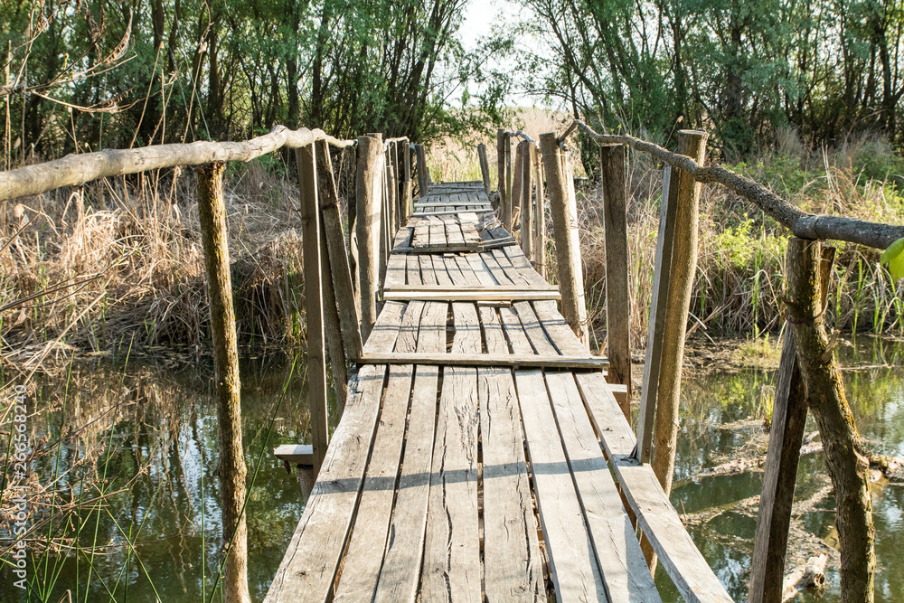 old dilapidated wooden plank bridge across river