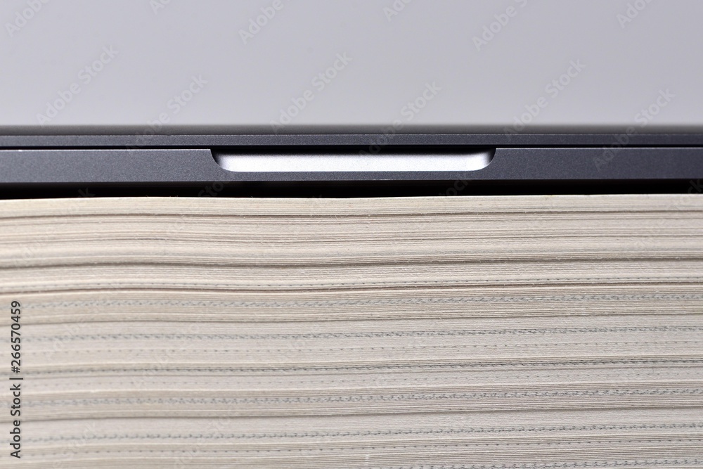Laptop computer stacked upon thick soft cover book Laptop computer stacked upon thick soft cover book
