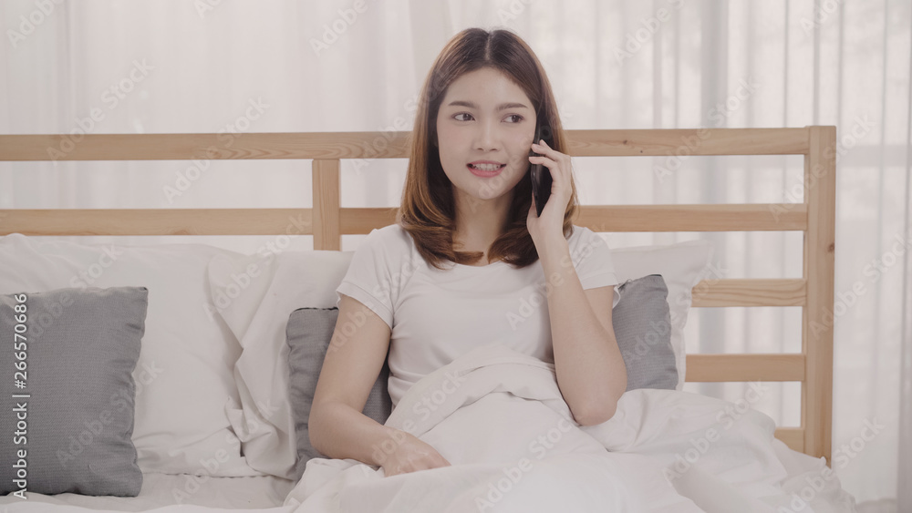 Young Asian woman using smartphone while lying on bed after wake up in the morning, Beautiful attractive Japanese girl smiling relax in bedroom at home. Enjoying time lifestyle women at home concept. Young Asian woman using smartphone while lying on bed after wake up in the morning, Beautiful attractive Japanese girl smiling relax in bedroom at home. Enjoying time lifestyle women at home concept.