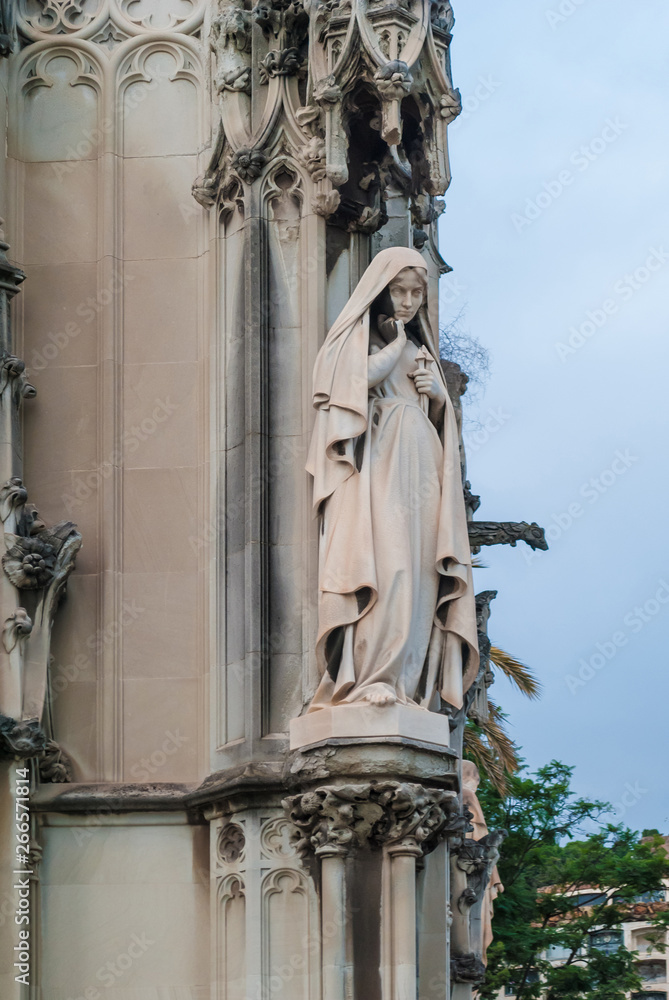 A statue of woman on the facade of the crypt on the Montjuic Cemetery in overcast day, Barcelona, Catalonia, Spain