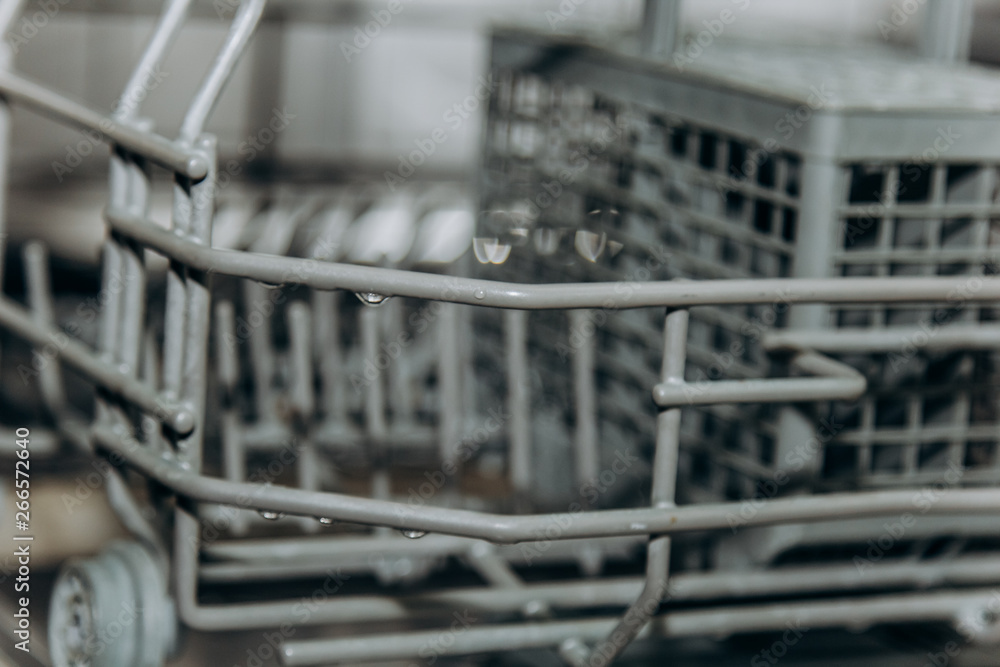 empty open dishwasher closeup. cutlery compartment close-up. household appliances in the kitchen macro empty open dishwasher closeup. cutlery compartment close-up. household appliances in the kitchen macro