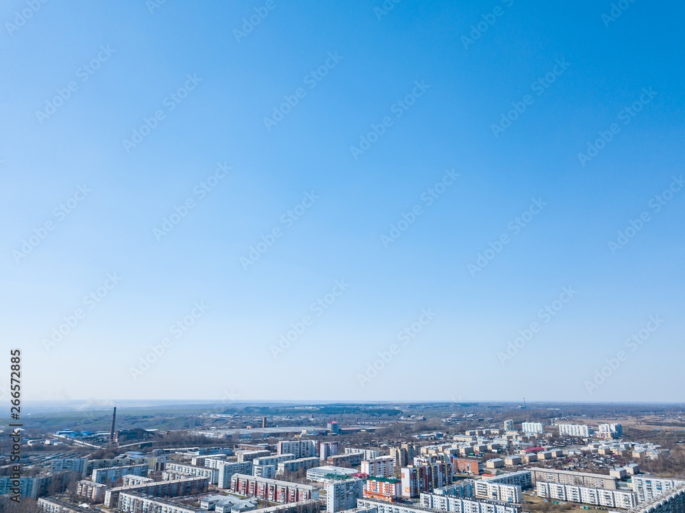 spring landscape from a aerial view of the small city of Leninsk Kuznetsk, of the streets with a road, tall buildings, houses with roofs under blue sky, parking lots, cars, trees. spring landscape from a aerial view of the small city of Leninsk Kuznetsk, of the streets with a road, tall buildings, houses with roofs under blue sky, parking lots, cars, trees.