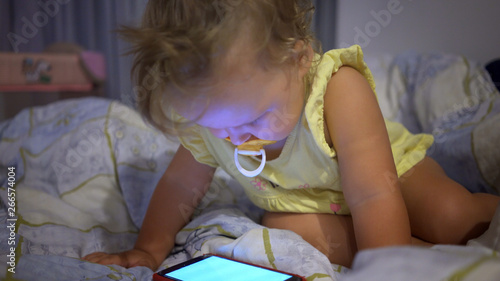 Wallpaper Mural Little girl with mobile phone in bed in the evening. Telephone addiction in children.  Torontodigital.ca