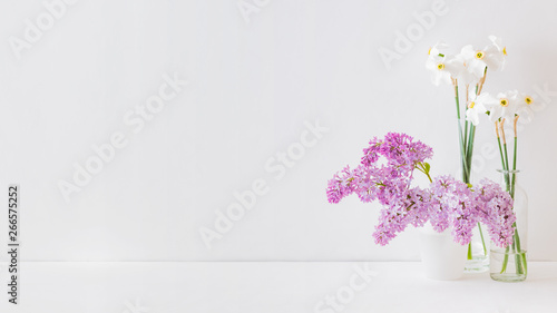 Home interior with decor elements. White daffodils in a vase on a white table