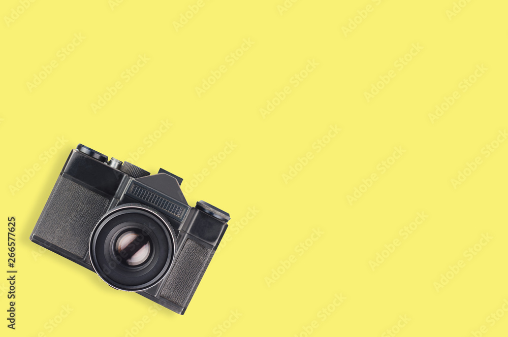 Old vintage camera for photo in center of yellow table. Top view. Travel concept. Copy space for your text