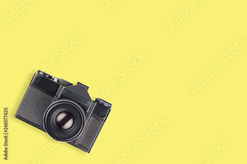 Old vintage camera for photo in center of yellow table. Top view. Travel concept. Copy space for your text