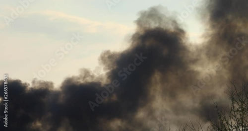 environmental destruction - dark grey smoke fills the sky as petrol leaks from a petroleum tank photo