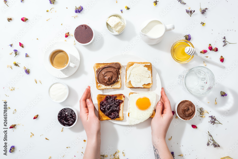 cropped view of woman with tattoo in hand holding plate with breakfast on white cropped view of woman with tattoo in hand holding plate with breakfast on white