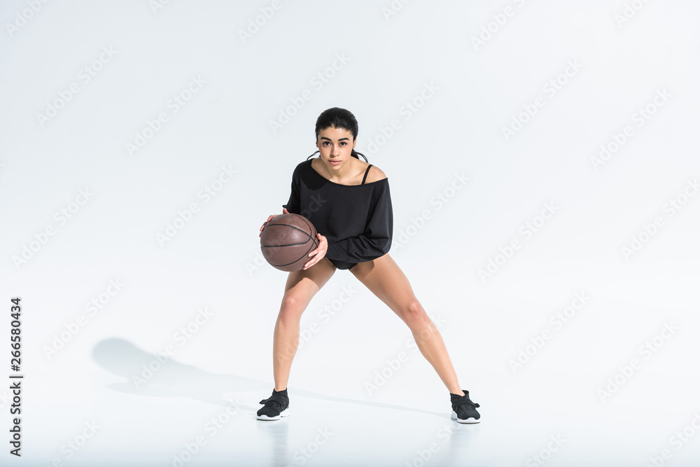 attractive african american girl with brown ball looking at camera on white background