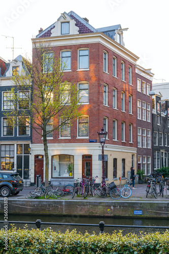 Amsterdam  Netherlands - April 09  2019  Classic bicycles and historical houses in old Amsterdam. Typical street in Amsterdam with canal and colorful houses in the Dutch style on the Sunset.