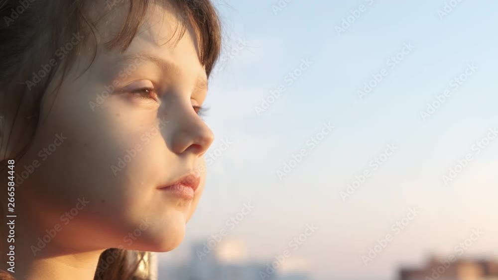 Portrait of a child looking out the window. A cute little girl looks out the window at the sunset. Portrait of a child looking out the window. A cute little girl looks out the window at the sunset.