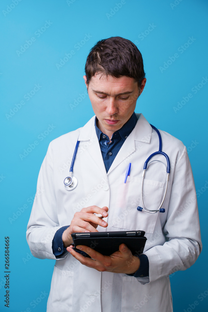 Portrait of doctor with stethoscope and tablet computer in hand on blue background Portrait of doctor with stethoscope and tablet computer in hand on blue background