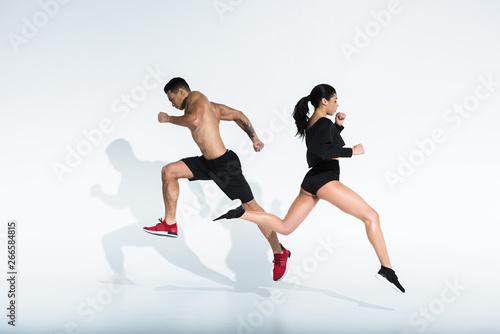sportive african american girl and athletic mixed race man running on white background