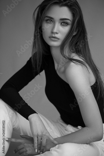 Fashion minimalist dark portrait of brunette female model on grey background. stylish clothing, black and white concept