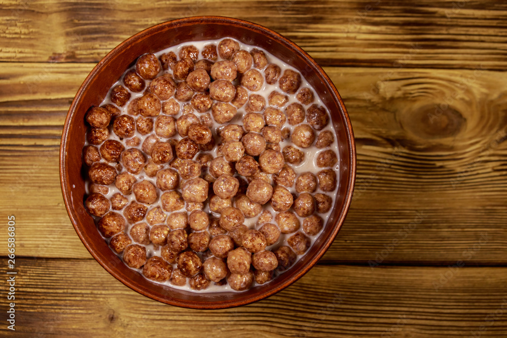 Cereal chocolate balls with milk in a bowl on wooden table. Top view Cereal chocolate balls with milk in a bowl on wooden table. Top view