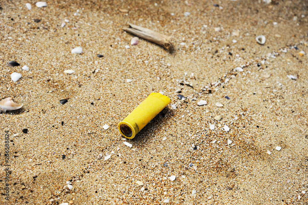 Hunting cartridge on the sand. Garbage on the beach. Dirty sea shore. Environmental pollution. Save the Planet. Ecological problem. Nature theme. Hunting cartridge on the sand. Garbage on the beach. Dirty sea shore. Environmental pollution. Save the Planet. Ecological problem. Nature theme.