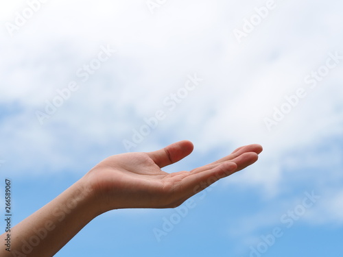 Empty open woman hand or face up hand against with blue sky and white clouds. © ieang