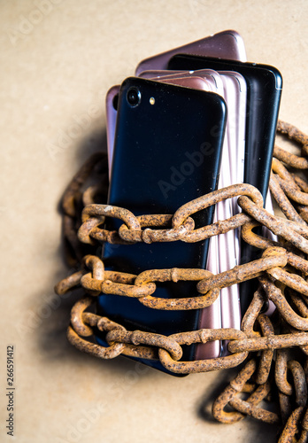 Smartphons in chains. Old rusty chains. Black smartphone. photo