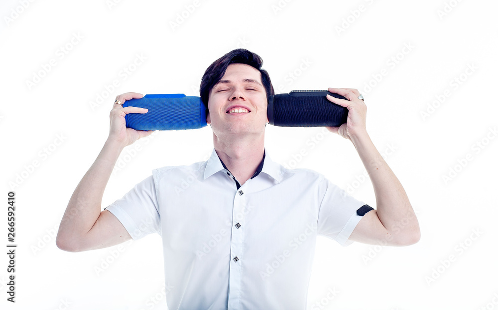 a young guy holding speakers on both sides of the ears, smiling and listening to music a young guy holding speakers on both sides of the ears, smiling and listening to music