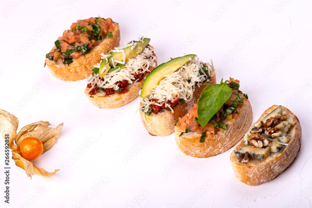 Variety of canape with hummus, tomato, avocado, cheese, walnut and fresh vegetables on white background. Top view of healthy snack concept. Variety of canape with hummus, tomato, avocado, cheese, walnut and fresh vegetables on white background. Top view of healthy snack concept.