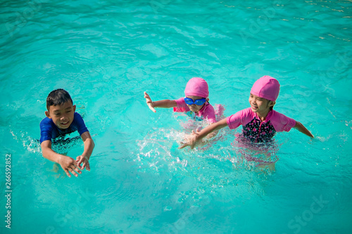 Happy kids swimming in swimming pool on summer season holiday