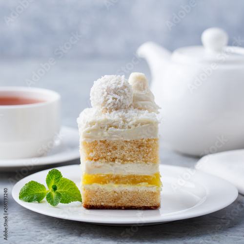 Coconut layered, raffaello cake on white plate. Grey background. Close up. photo