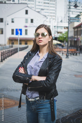 beautiful stylish girl in a black leather jacket, jeans and sunglasses