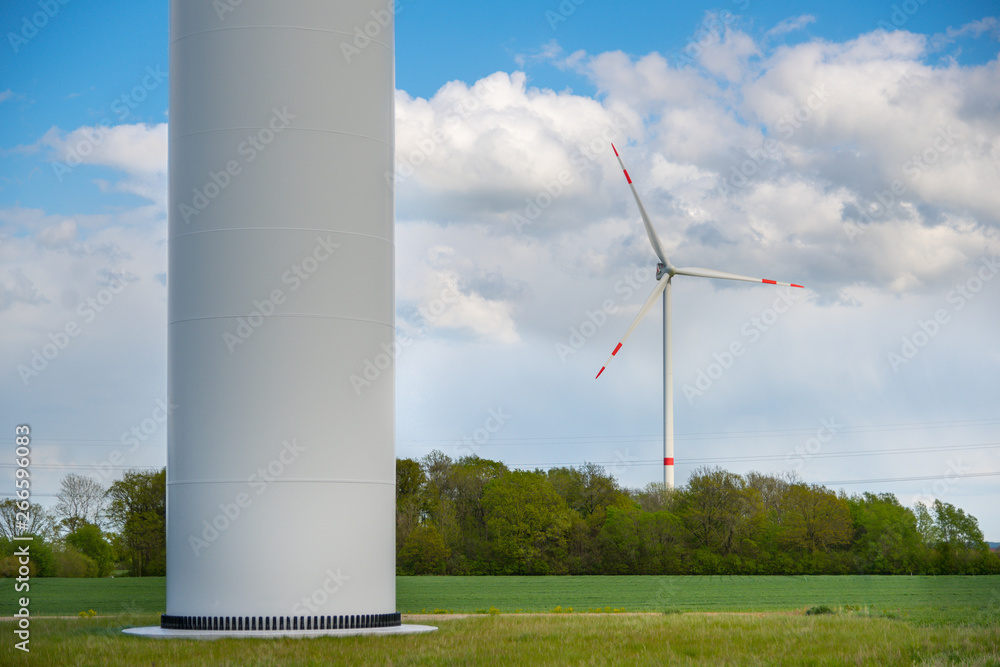 Windkraftanlage und Sockel vor blauem Himmel und weißen Wolken für alternative und erneuerbare Energie Windkraftanlage und Sockel vor blauem Himmel und weißen Wolken für alternative und erneuerbare Energie