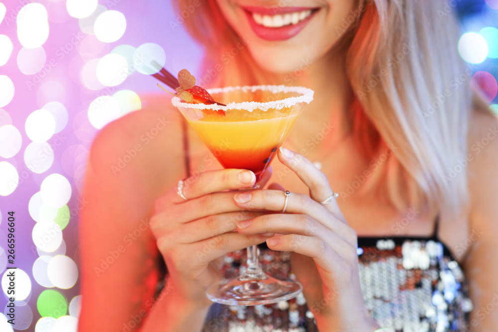 Φωτογραφία Young woman with glass of martini cocktail against festive lights, closeup