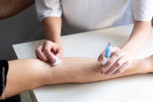 Close-up nurse hands with syringe doing an injection to the patient of a hospital. Doing anesthesia before a surgery. Healthcare therapy.