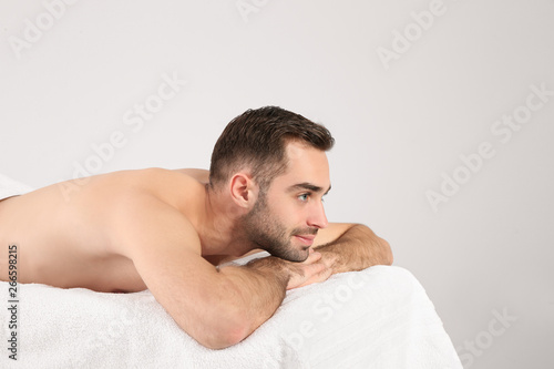 Handsome man relaxing on massage table against white background. Spa service