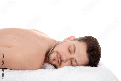 Handsome man relaxing on massage table against white background. Spa service