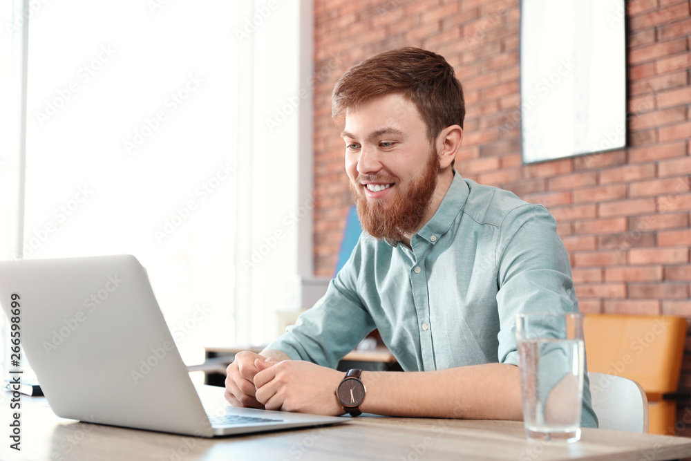 Young man using video chat on laptop in home office Young man using video chat on laptop in home office