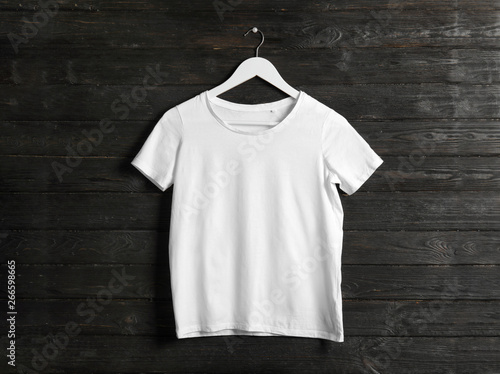 Hanger with white t-shirt on wooden background. Mockup for design