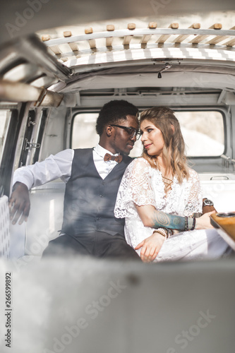 Happy couple hugging while sitting inside in retro minivan at sunset in canyon - Young people having fun on summer beach vacation - Travel and love concept - Focus on faces © sofiko14