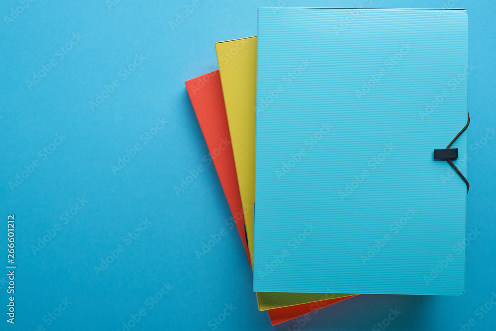 top view of colorful paper binders isolated on blue with copy space - obrazy, fototapety, plakaty 