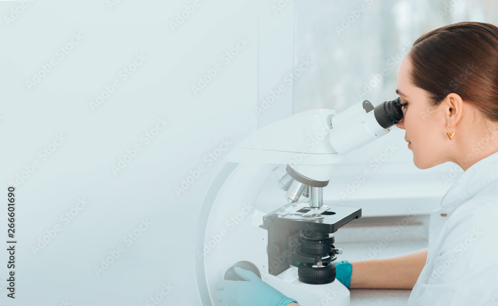 Scientist Looking Through Microscope and concentrate. Scientist examining a human sample on a glass slide at laboratory Scientist Looking Through Microscope and concentrate. Scientist examining a human sample on a glass slide at laboratory