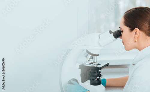 Scientist Looking Through Microscope and concentrate. Scientist examining a human sample on a glass slide at laboratory