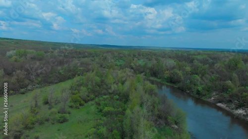 Sunny summer landscape with river.Green hills,fields and meadows.River Medvedica in Volgograd region,Russia.Sunrise.Quiet morning.Calm.Warm sunlight.Cloudless clear blue sky. 